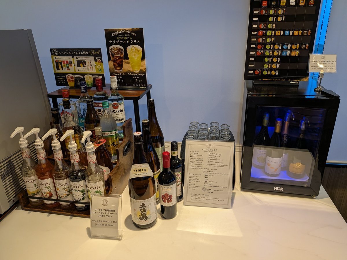 リキュールやカクテル用シロップ、日本酒、ワインなど多種多様なアルコールが並ぶドリンクバー。右奥にはスパークリングワインの冷蔵庫も見える。