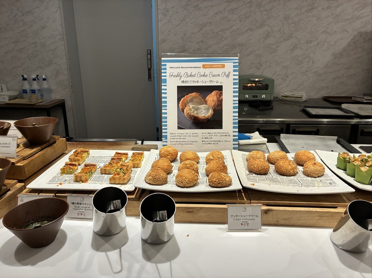「焼き立てクッキーシュークリーム」の案内板が立つデザートコーナー。サクサクしたシュークリームや、野菜のキッシュのような軽食が複数並べられている。