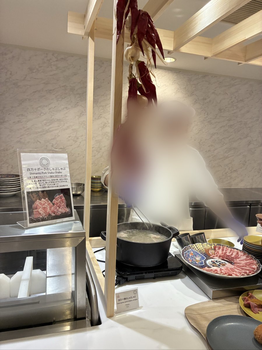 「四万十ポークのしゃぶしゃぶ」の案内板があるライブキッチンコーナー。調理用の鍋が置かれ、薄切りにされた豚肉が美しく盛り付けられている。
