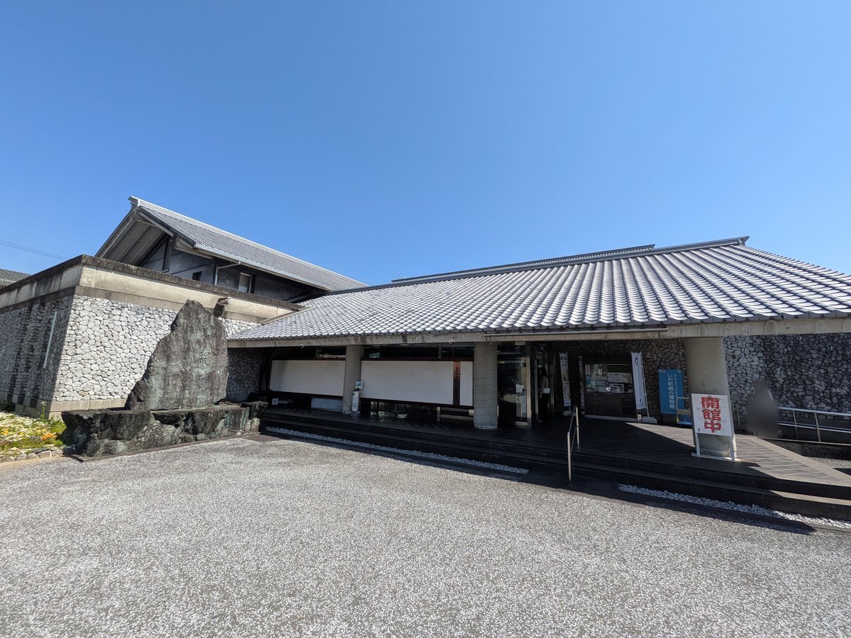 青空の下、瓦屋根と石垣が特徴的な「いの町紙の博物館」の建物外観。入口付近には大きな石碑が設置されている。