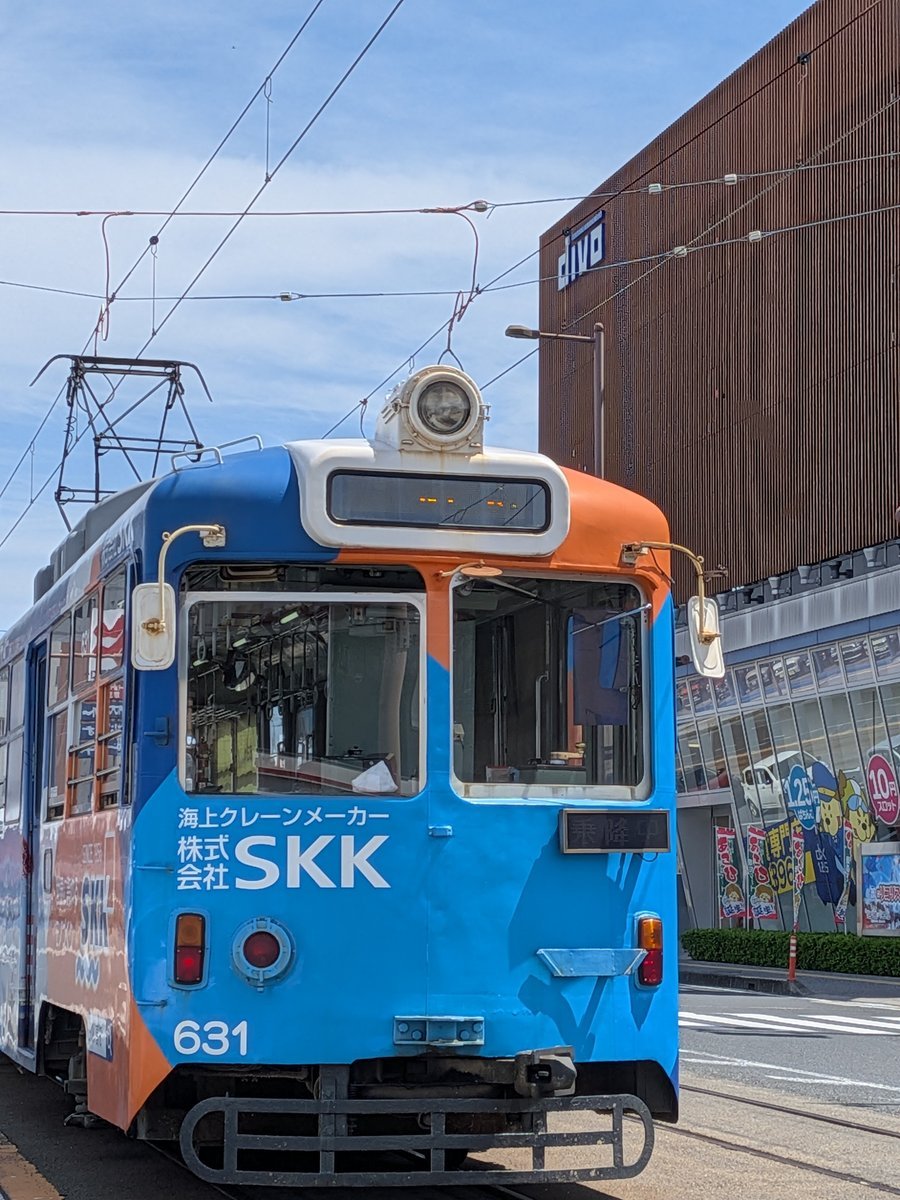 青とオレンジ色の車体が特徴的な、とさでん交通の路面電車が街中を走る様子。