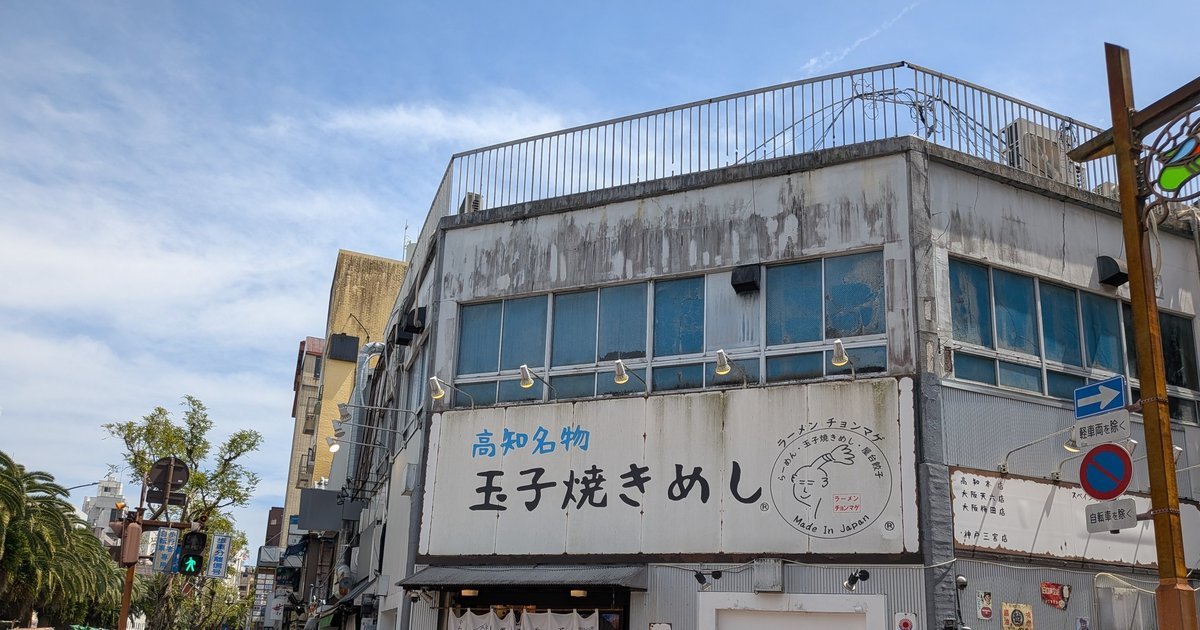 雑居ビルの1階にある店舗の外観。白地に「高知名物 玉子焼きめし」と書かれた大きな看板が特徴的で、上部には「らーめん チョンマゲ」のロゴも見える。