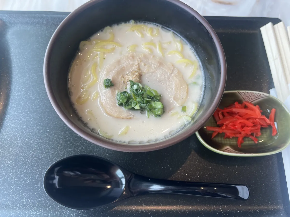 クリーミーなとんこつスープの細麺ラーメン。チャーシューと青ねぎ、紅生姜が添えられている。