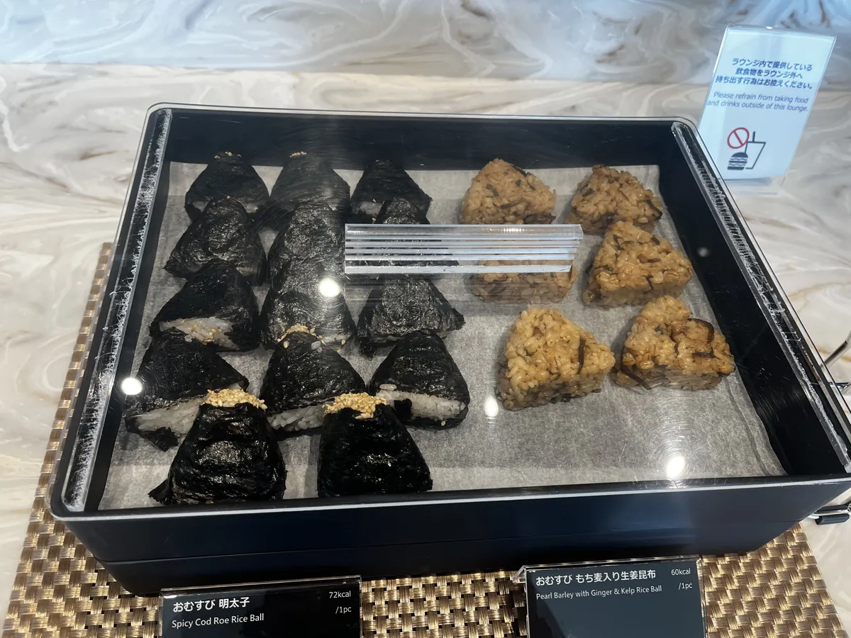 ガラスケースのおにぎり。明太子ともち麦入り生姜昆布の海苔巻きおにぎりが整然と並ぶ。