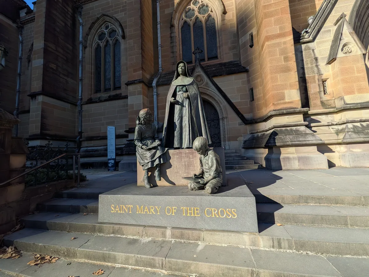 セント・メアリー大聖堂の階段脇に立つ SAINT MARY OF THE CROSS(メアリー・マッキロップ)の銅像。修道女と二人の子どもをかたどった彫刻群