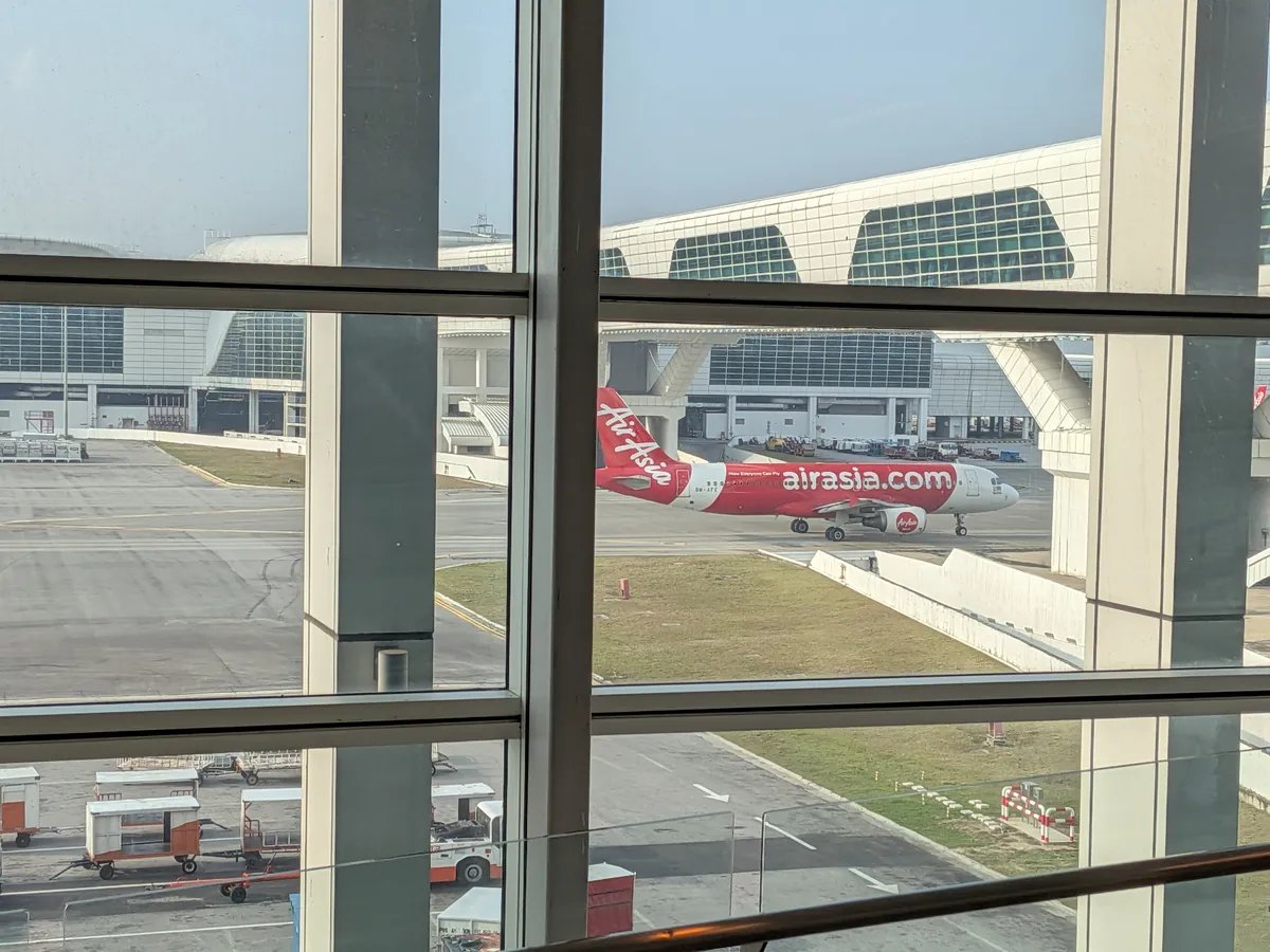 ターミナルの窓越しに見えるエアアジアの機体。赤い胴体にairasia.comのロゴ