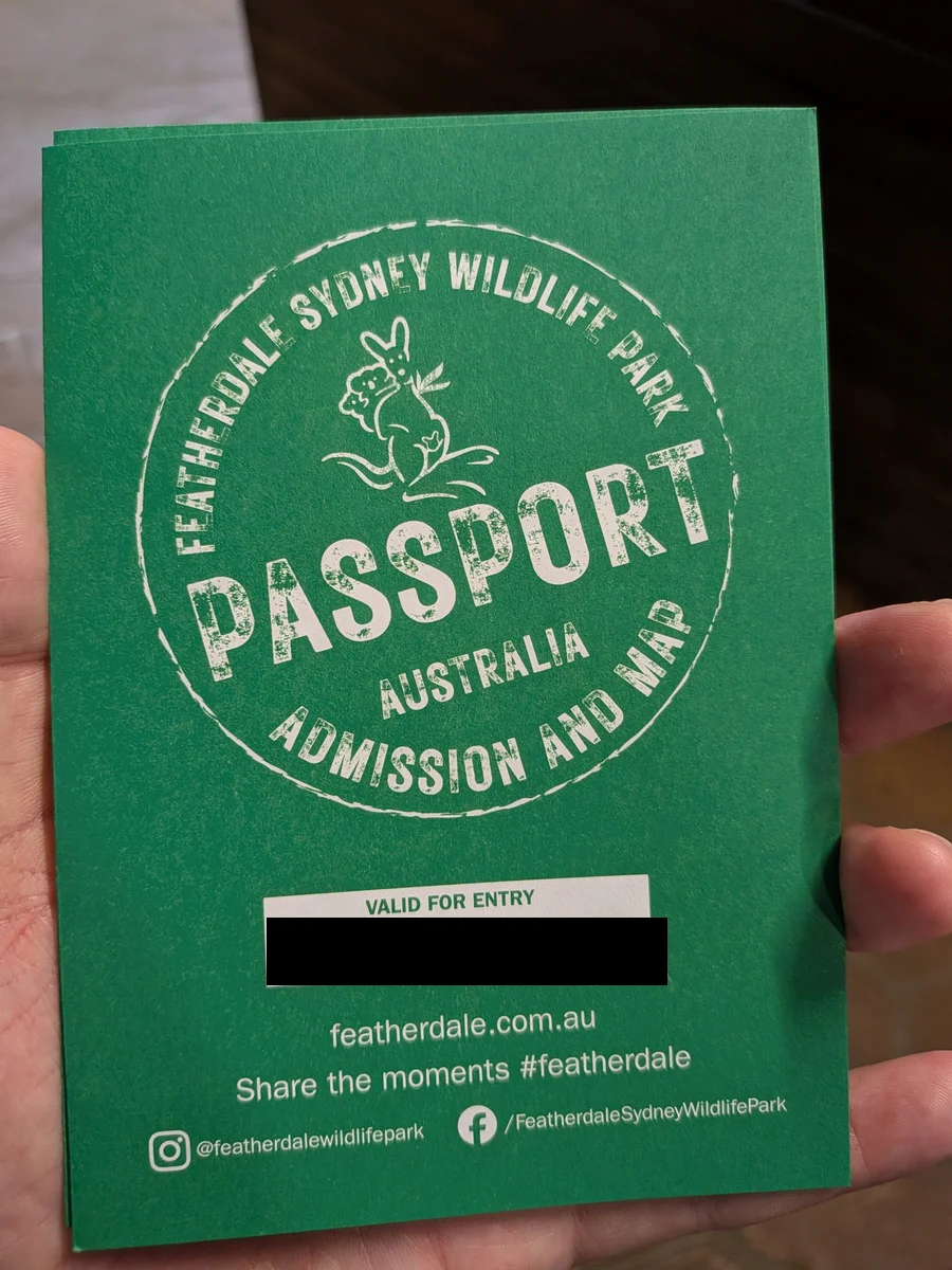 入口で受け取る紙のチケット。「FEATHERDALE SYDNEY WILDLIFE PARK PASSPORT ADMISSION AND MAP」とスタンプ風にデザインされた緑の券面(有効日は黒塗り)