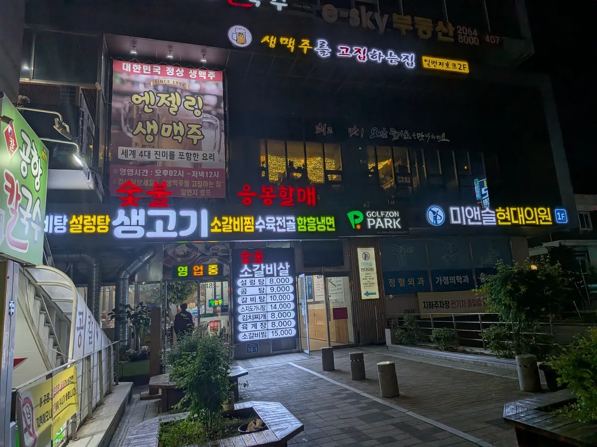 空港カルグクスが入る雑居ビルの外観（夜）。看板が並ぶ
