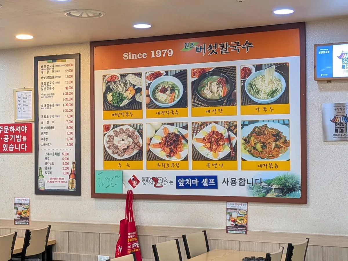 元祖きのこカルグクス（Since1979）のメニュー看板。きのこカルグクスなど料理写真が並ぶ