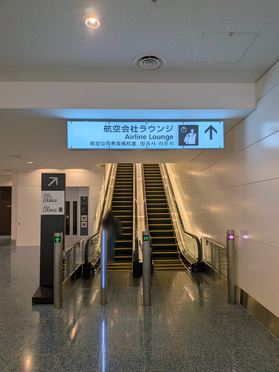 羽田空港第2ターミナル国際線、出国後のエスカレーターと「航空会社ラウンジ／Airline Lounge」の案内サイン