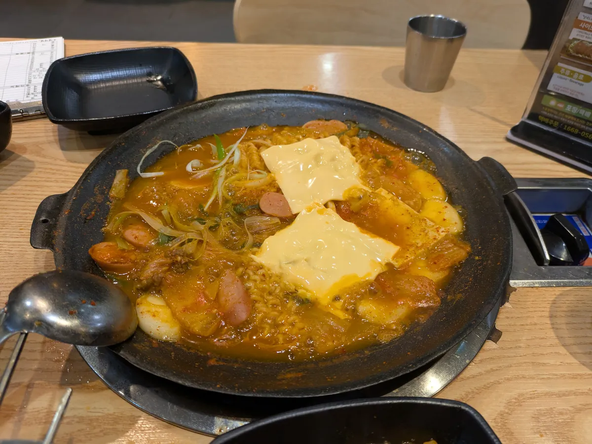 煮込まれた部隊チゲ。スパム・ソーセージ・チーズ・ラーメン入りの旨辛鍋