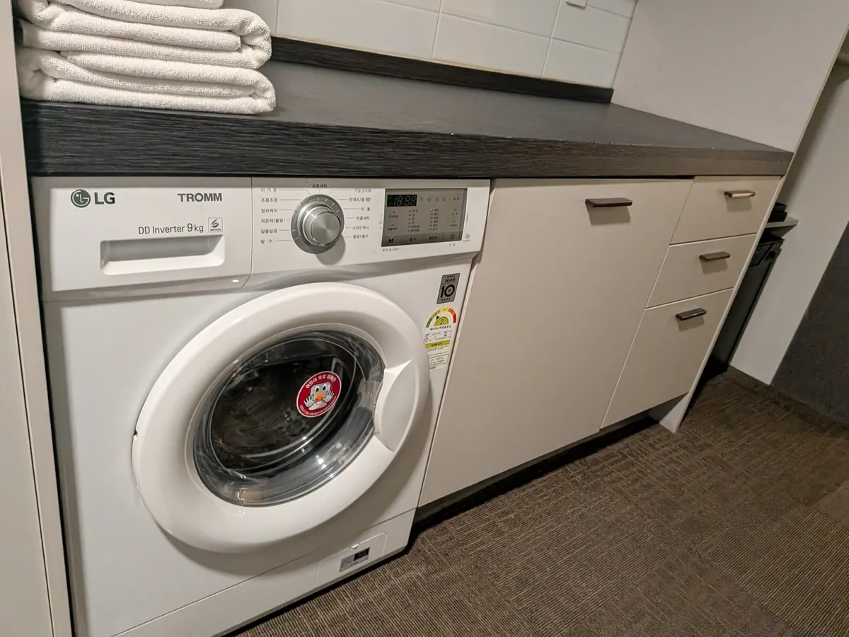 客室内に備え付けられたLG TROMMのドラム式洗濯機（DD Inverter 9kg）。上にはタオル