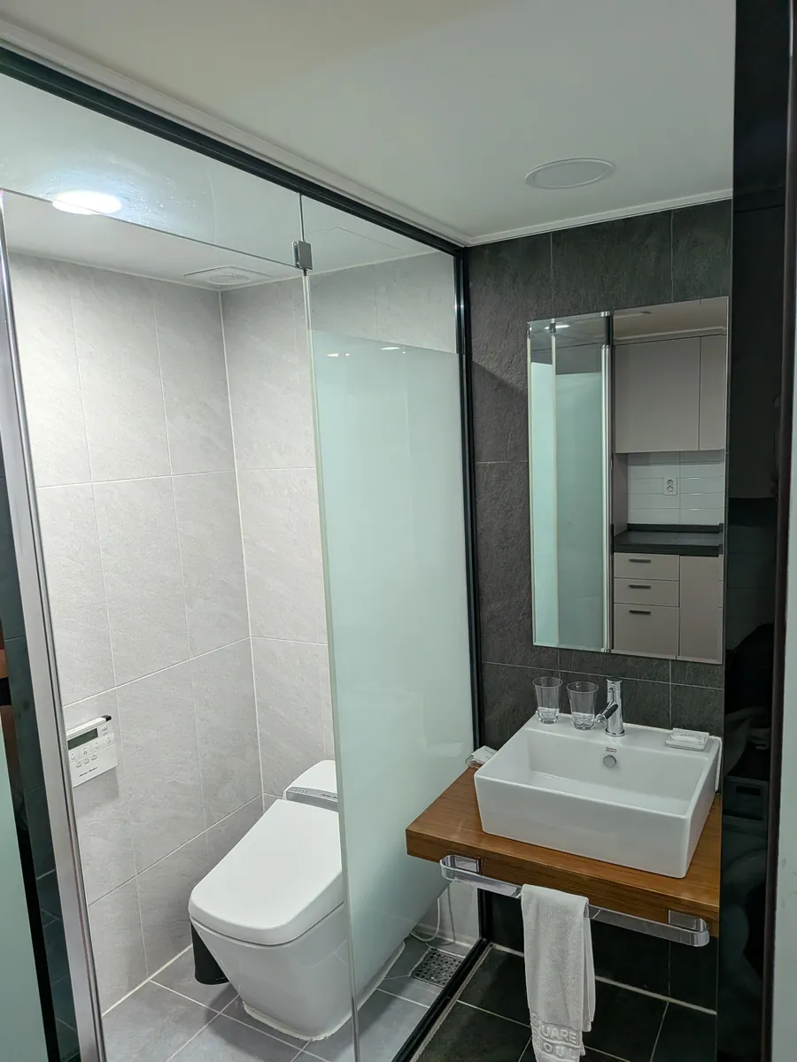客室の水回り。ウォシュレット付きトイレとベッセル型の洗面ボウル、ミラーキャビネット