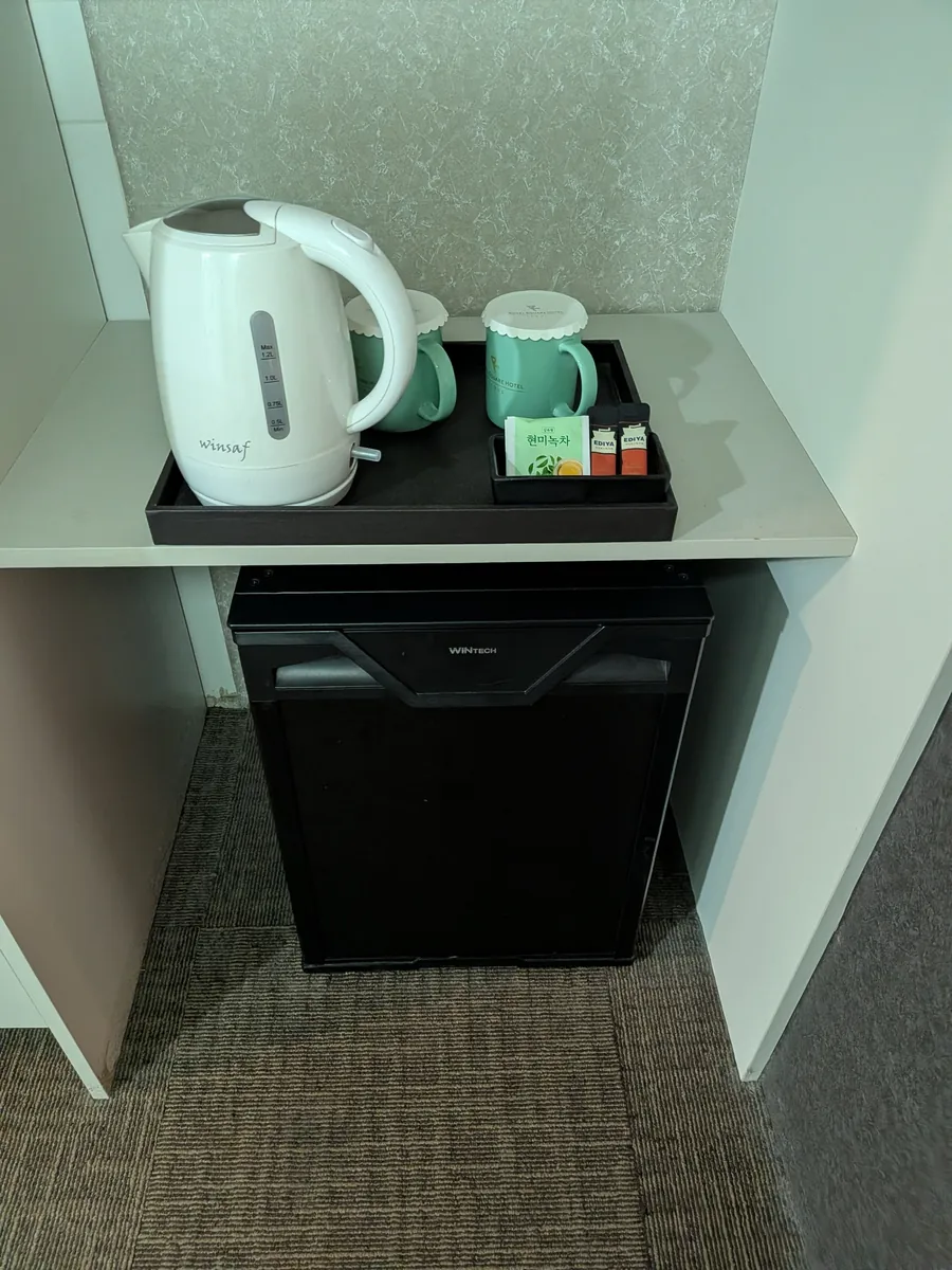 客室の備品。電気ケトルとホテル名入りのマグ、緑茶・コーヒースティック、下にミニ冷蔵庫