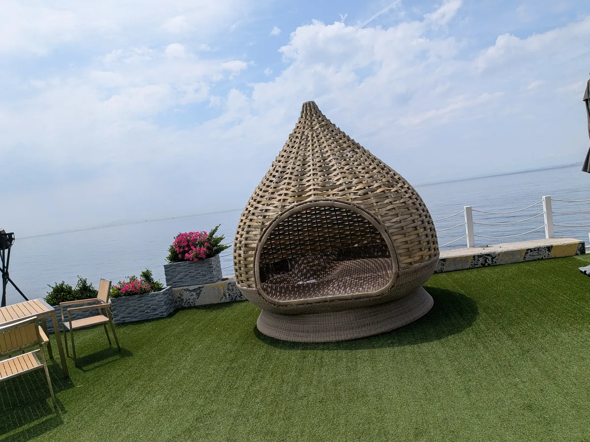 海辺の芝生に置かれた鳥の巣型のラタンチェア（フォトスポット）