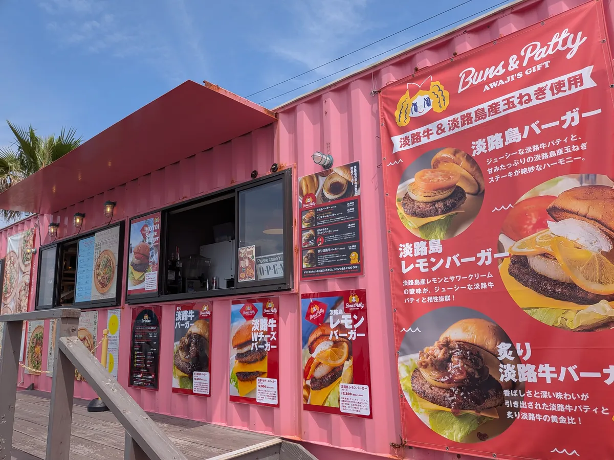 ピンクのコンテナ店Buns & Pattyの外観と淡路島バーガーのメニューポスター