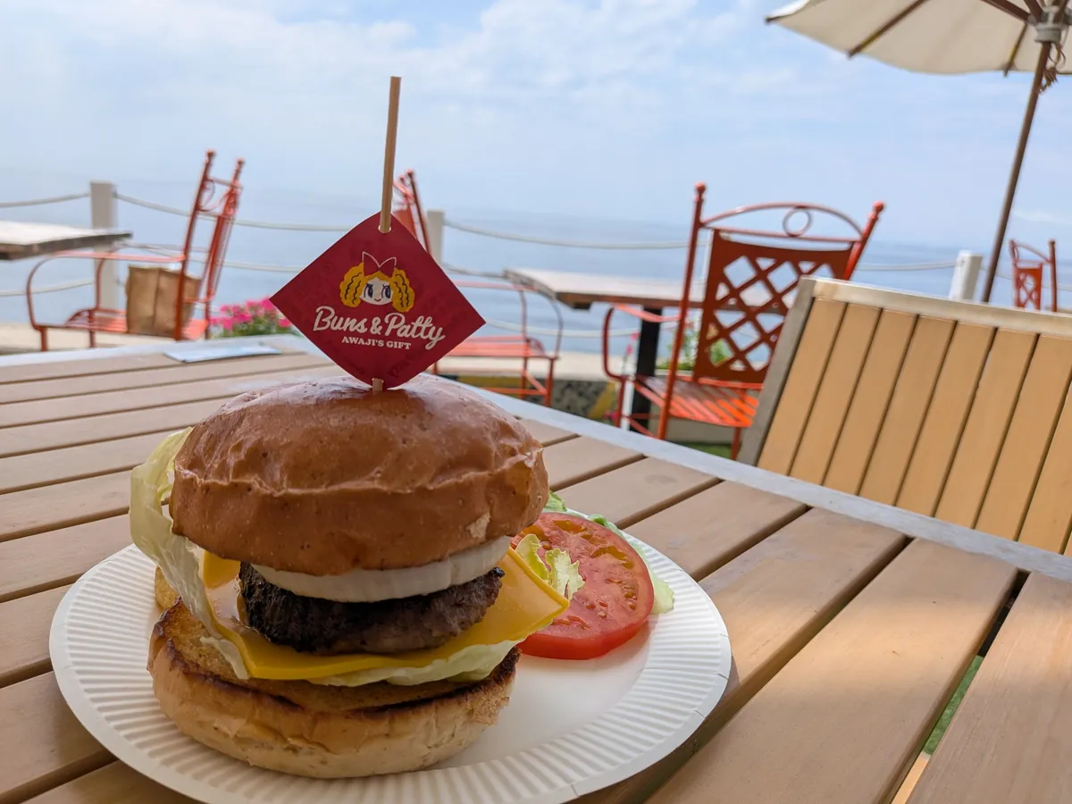 海を望むテーブルに置かれた玉ねぎステーキ入りの淡路島バーガー