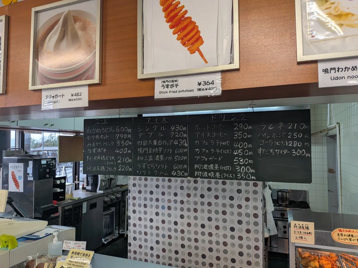 売店のメニュー黒板。わかめうどん600円・うずポテ400円・鳴門金時芋ソフト600円などの価格表