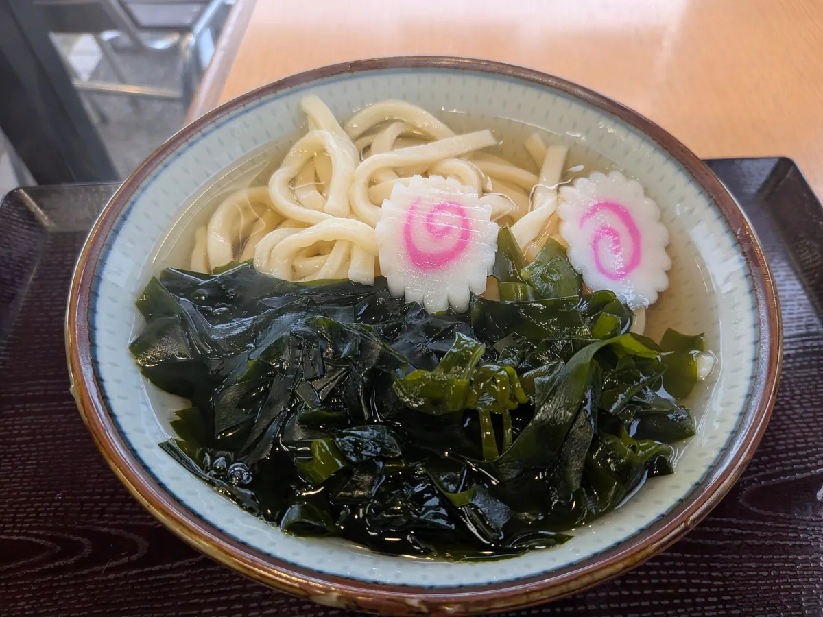 わかめうどん。生の鳴門わかめがたっぷり乗り、渦巻き模様のかまぼこをあしらった一杯