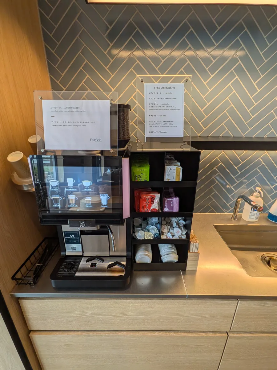 共用ラウンジのフリードリンクコーナー。コーヒーマシンと無料ドリンクメニュー