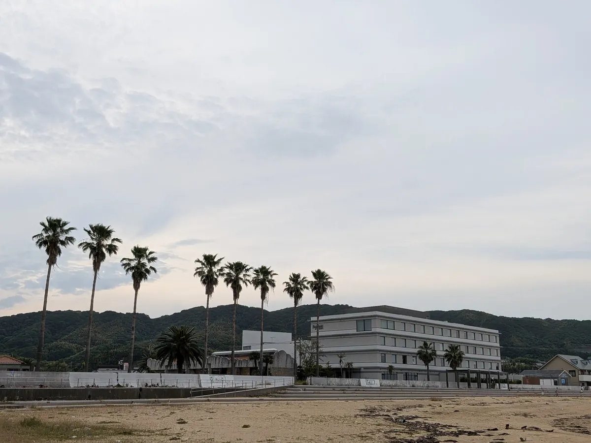 椰子の木と砂浜越しに見るフェアフィールド兵庫淡路島東浦の外観
