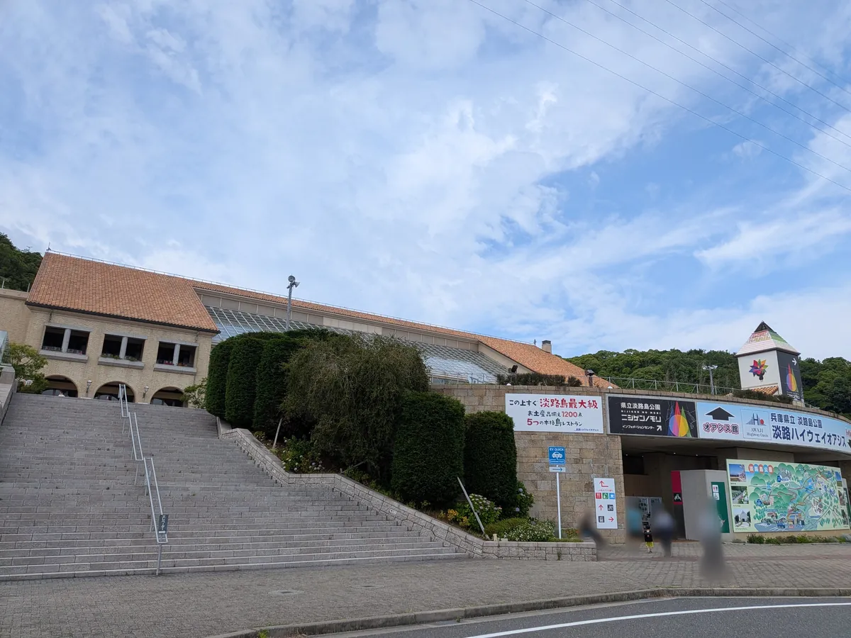 淡路ハイウェイオアシスの外観。レンガ屋根の建物と大階段、青空