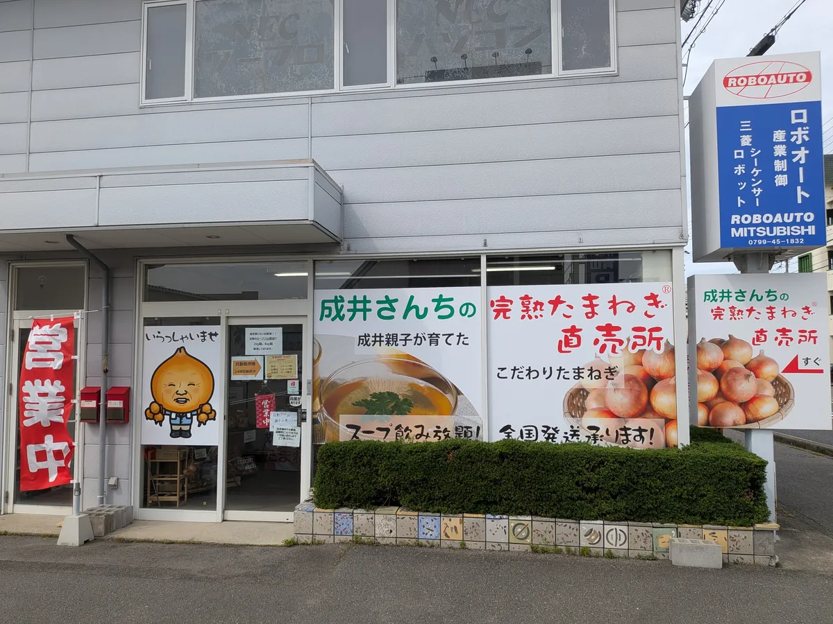 成井さんちの完熟たまねぎ直売所の店舗外観。営業中の看板と玉ねぎキャラが描かれた淡路島の玉ねぎ直売所