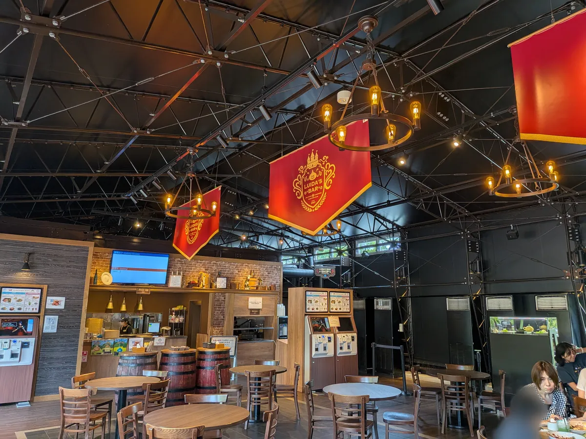 ルイーダの酒場の店内。赤いバナーと照明、テーブル席
