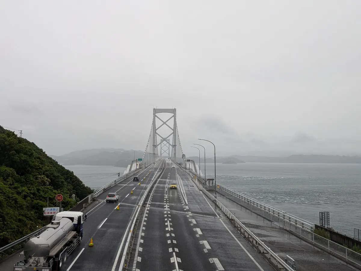 渦の道から望む雨に煙る大鳴門橋の橋上と鳴門海峡