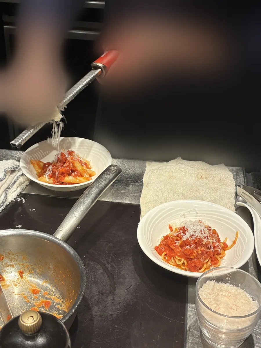 目の前でパスタにチーズを削りかけて仕上げるライブキッチンの実演