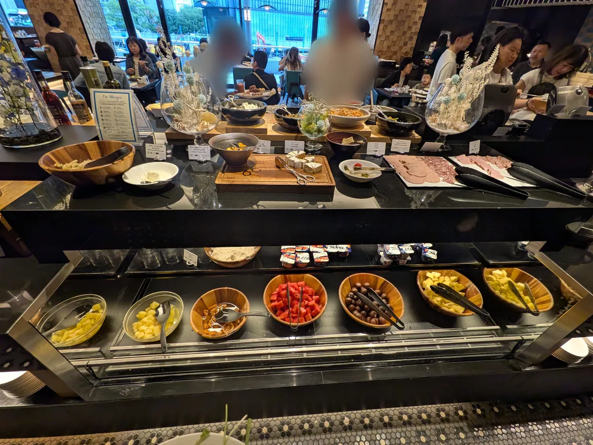 ヒルトン大阪フォルクスキッチン 朝食ビュッフェ会場全景 卵・フルーツ・チーズ・ハムが並ぶ黒カウンター