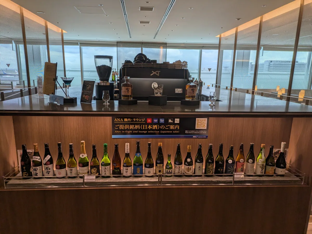 ANA機内・ラウンジ提供の日本酒約20銘柄がずらりと並ぶバー。田酒・而今・獺祭などのボトル。