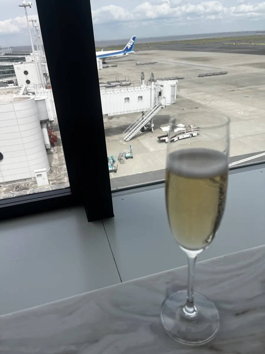 窓際に置かれたシャンパングラス越しに、駐機中のANA機とタラップが見える滑走路ビュー。