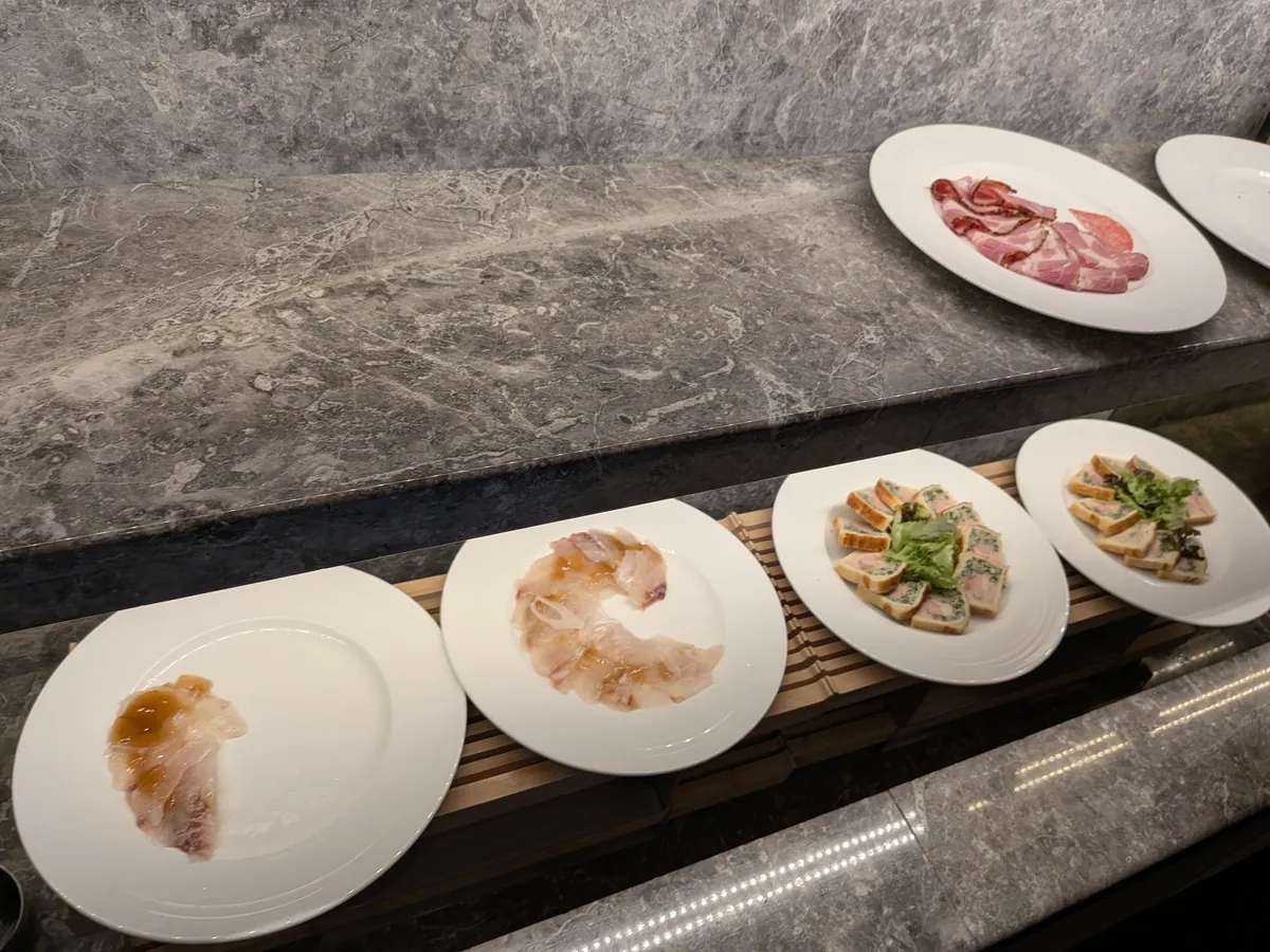 カクテルタイムの冷製オードブルの大皿。お魚のカルパッチョ、ペッパーシンケンやサラミ、彩りのテリーヌがビュッフェ台に並ぶ