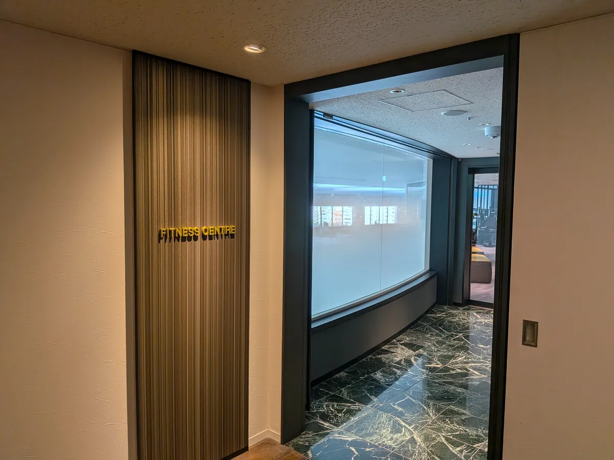 リーガロイヤルホテル大阪 アネックス7階のフィットネスセンター（FITNESS CENTRE）入口。金の館名サインと大理石の廊下、ガラス越しにジム