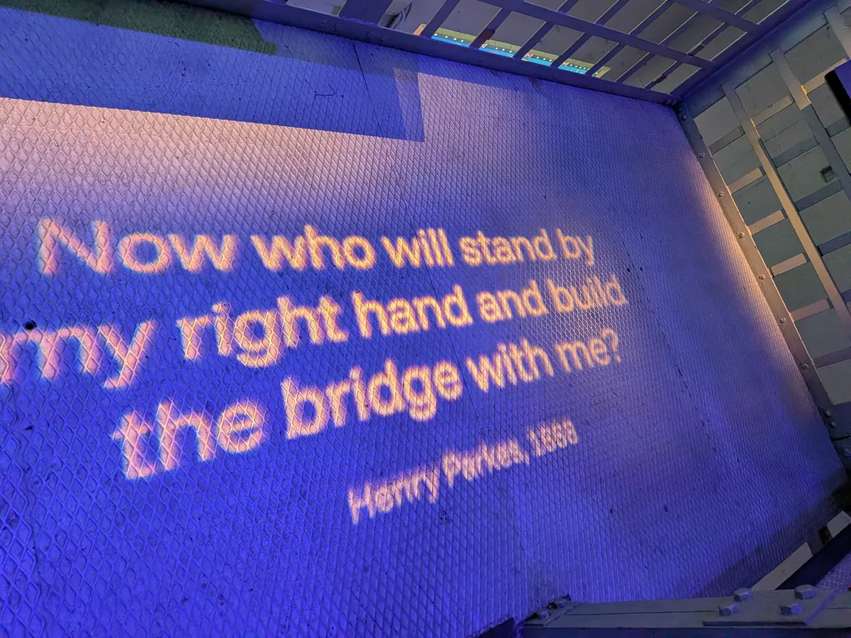 床に投影されたヘンリー・パークスの1888年の言葉「Now who will stand by my right hand and build the bridge with me?」