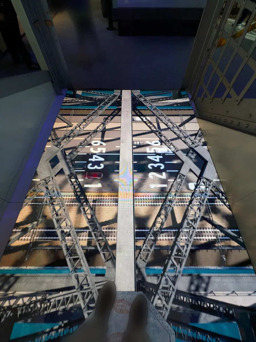 BridgeMuseum館内の床に埋め込まれたスクリーン。真下を見下ろす映像で、橋の鉄骨越しに車道が見える