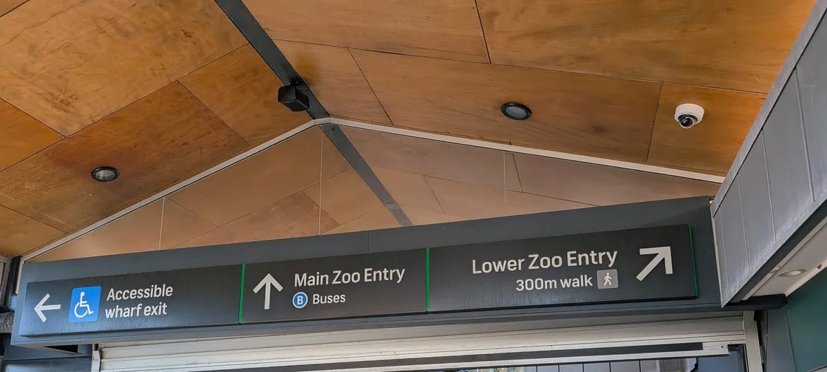 タロンガ動物園ワーフの頭上サイン。Main Zoo Entry（バス）、Lower Zoo Entry 300m walk、Accessible wharf exit の3方向表示