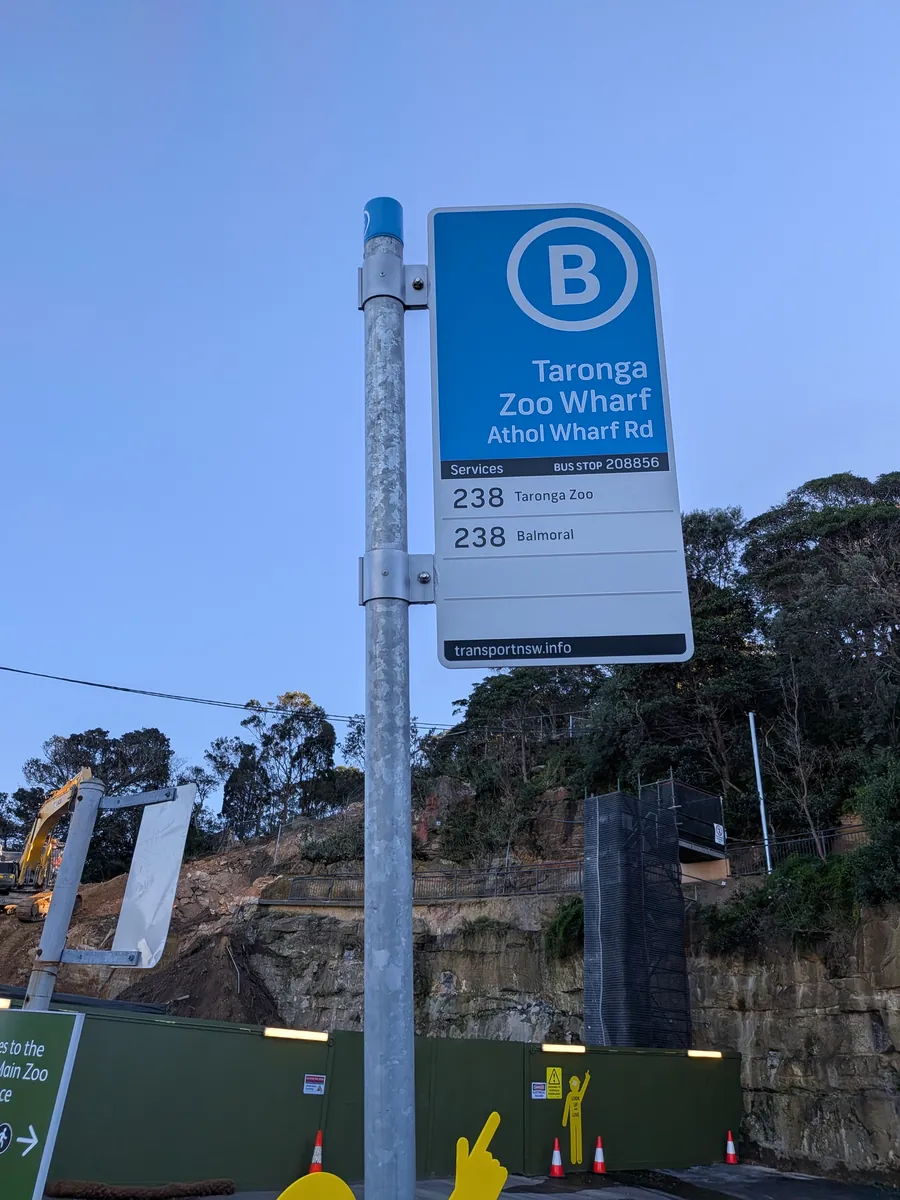 青い丸にBのバス停標識「Taronga Zoo Wharf」。背景は岩壁と木立