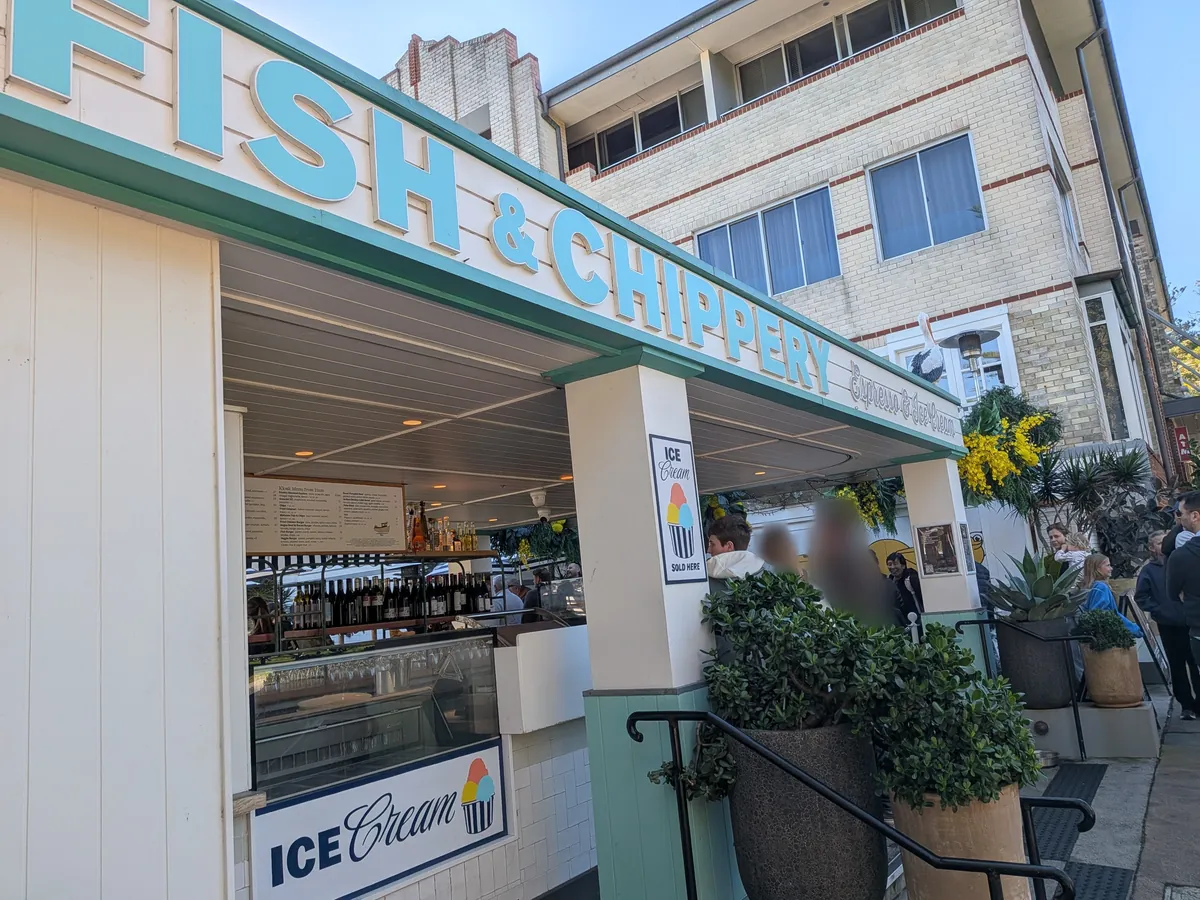 FISH & CHIPPERY の白と緑の建物。ICE CREAM の看板と植栽