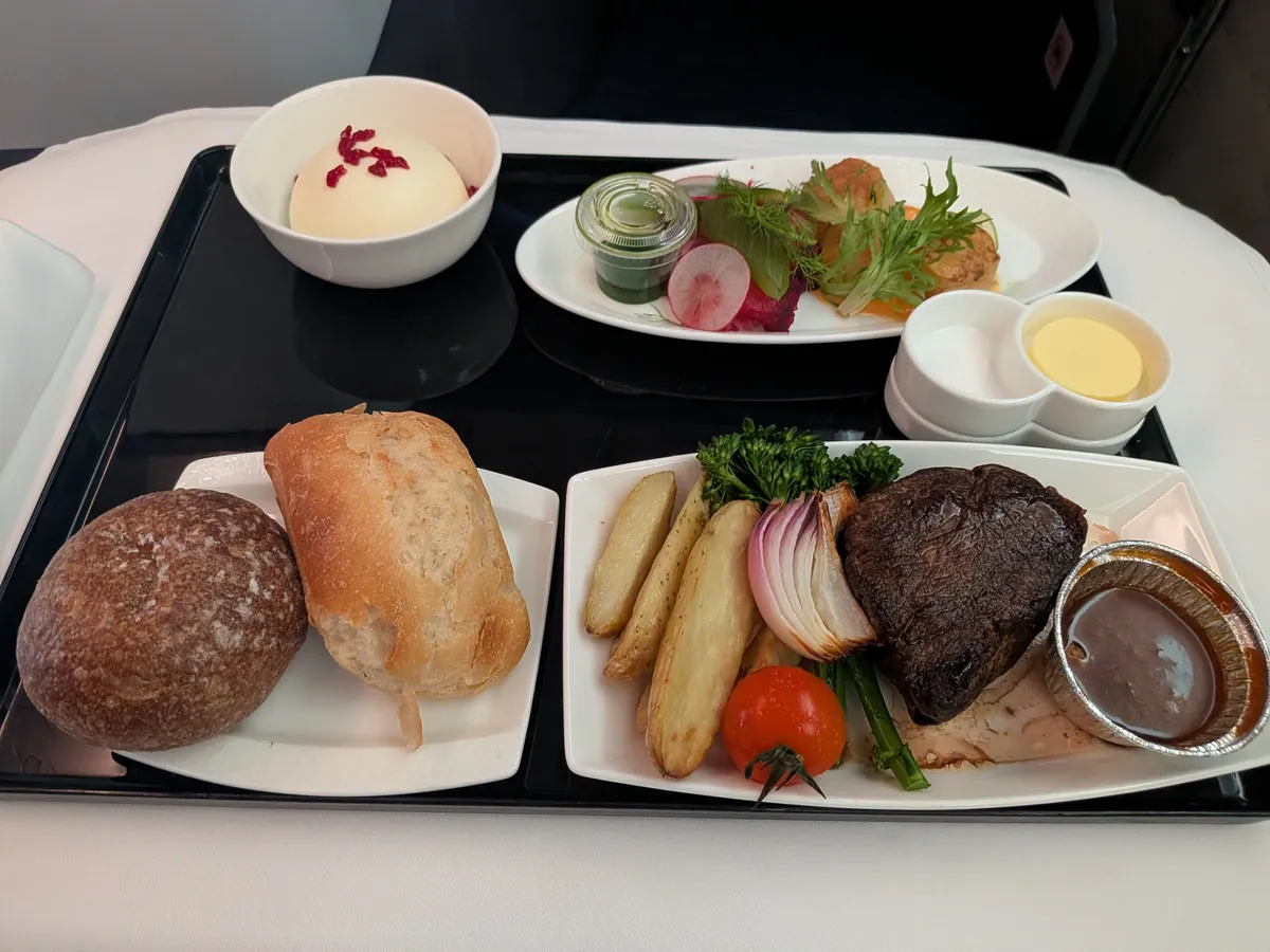復路の洋食。牛フィレ肉のステーキ ポルチーニソース、ポテト・野菜・前菜・パンのトレイ