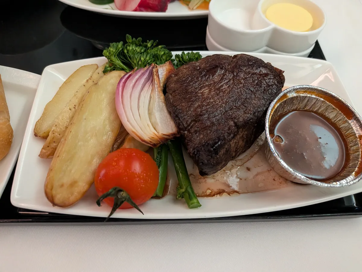 牛フィレ肉のステーキのクローズアップ。付け合わせの野菜と別添えソース