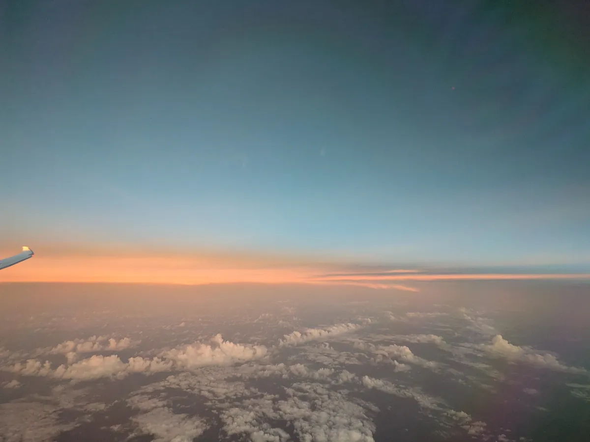 機内の窓から見た雲海を染める朝焼けと主翼