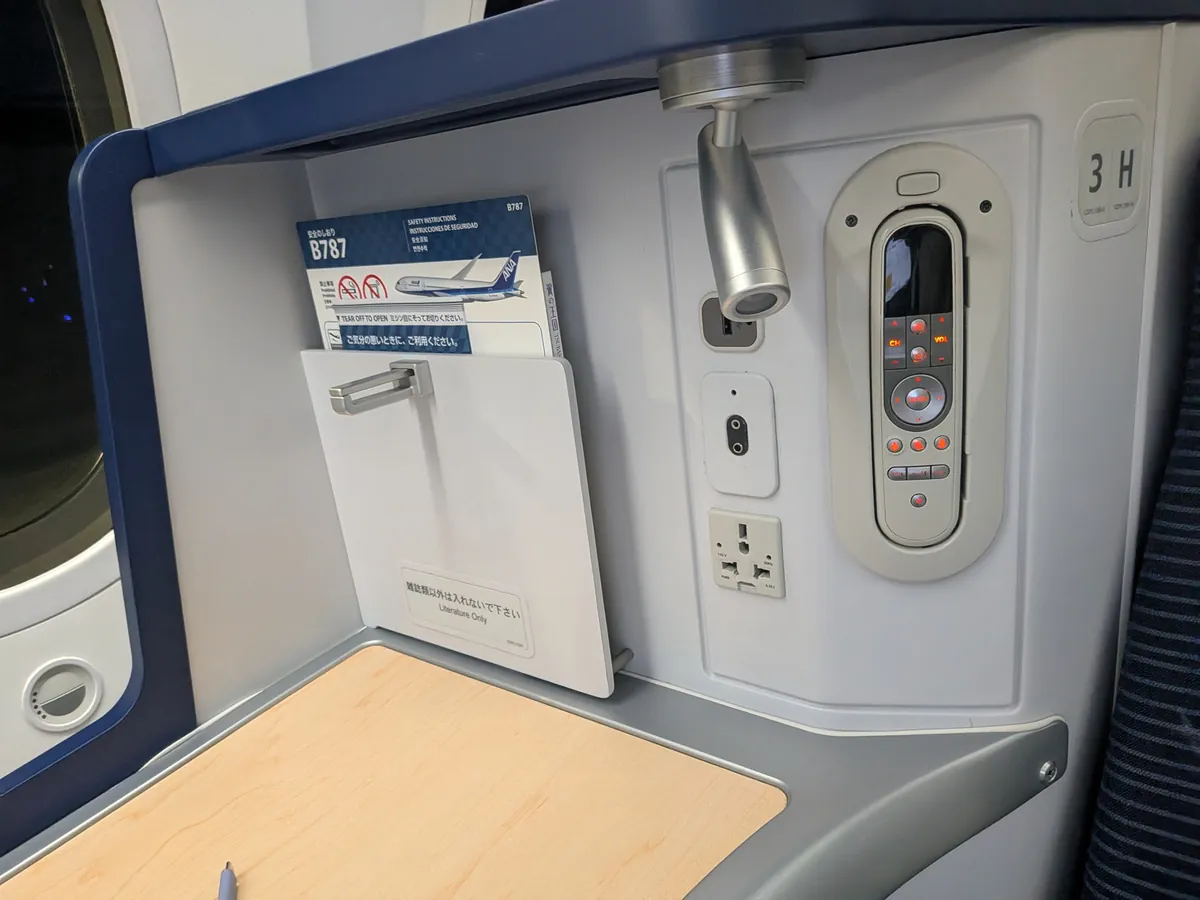 ビジネスクラス座席のコントロール周り。B787安全のしおり・リモコン・ユニバーサル電源コンセント