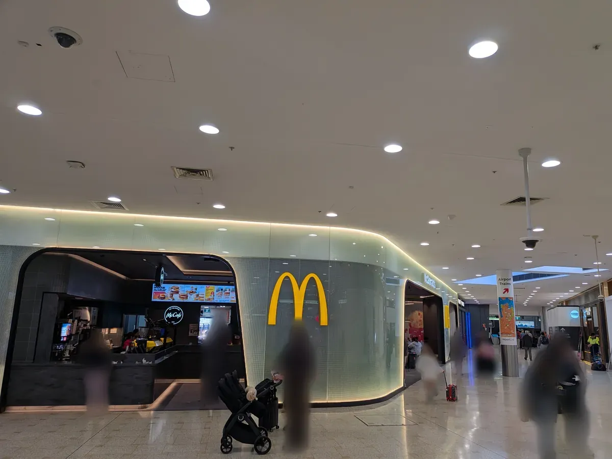 シドニー空港到着階のマクドナルドとAirport Trains(電車)への案内サイン