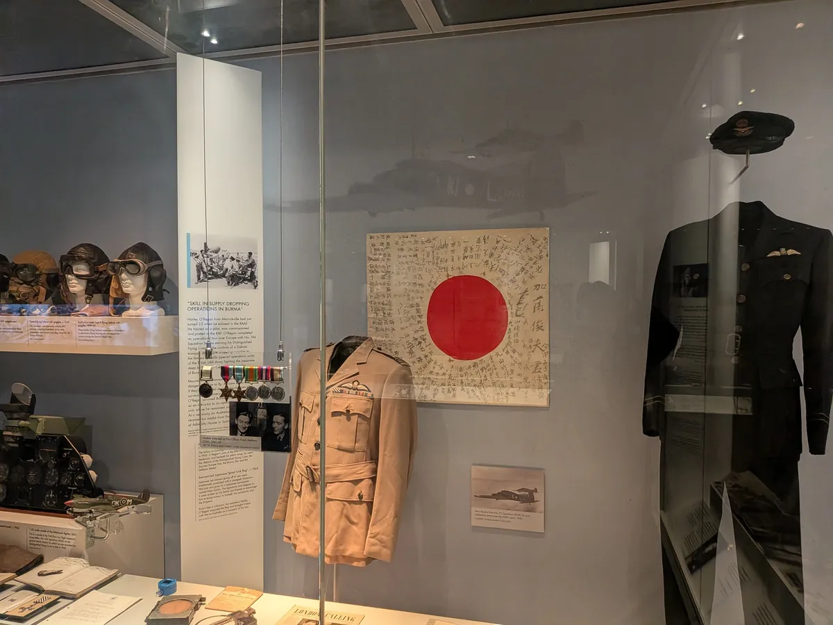 展示ケースの中の、墨で寄せ書きが書かれた日本の日の丸の旗とオーストラリア空軍の軍服
