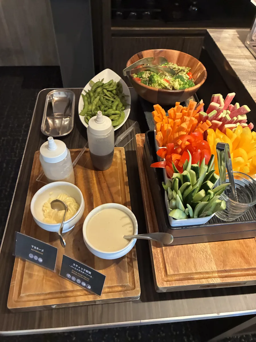ラウンジのサラダとスティック野菜、枝豆、ディップソースが木製トレーに並ぶコーナー