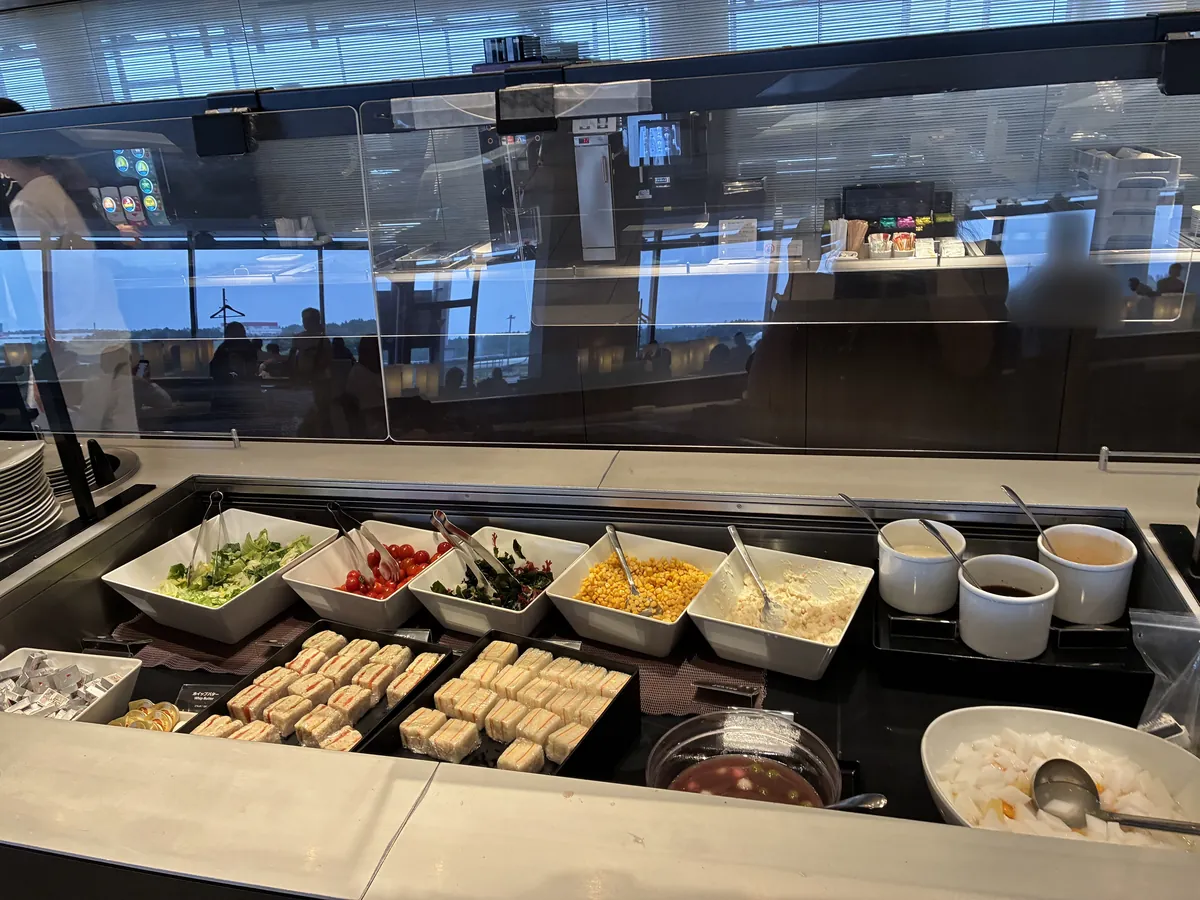 ラウンジのビュッフェカウンター。新鮮なサラダ、ミニサンドイッチ、フルーツポンチなど、バラエティ豊かな食事が並べられている。