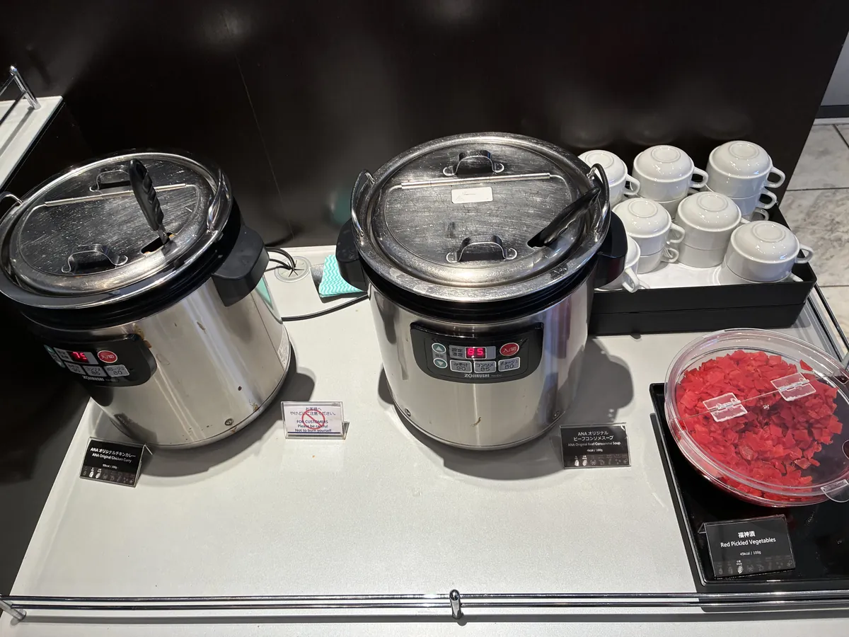 カレーとANAオリジナルコンソメスープが提供されている保温器。隣には福神漬けも用意されている。