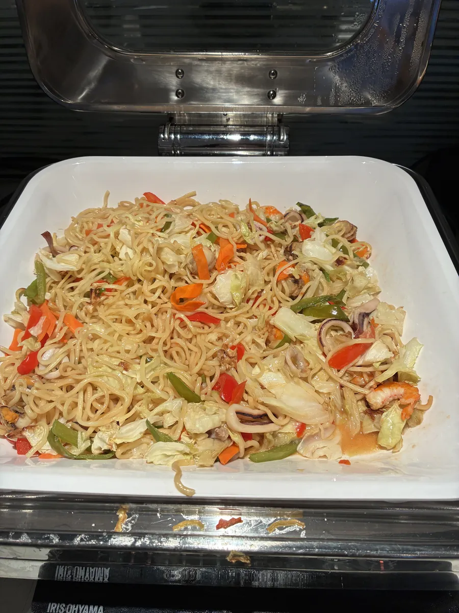ラウンジの温かい料理コーナーに並べられた、野菜とシーフードが入った焼きそば風の麺料理。